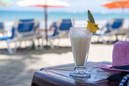Coconut shake pina colada drink cocktail milkshake at beach bar. Ocean view with tall milk drinking glass on table.の写真素材