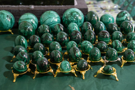 Display of polished malachite spheres and eggs on a green surface, highlighting unique patterns and colors, perfect for collectors and decorative accentsの写真素材