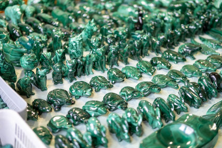 Display of various green malachite animal figurines arranged in neat rows, highlighting the intricate craftsmanship and vibrant colors of the market sceneの写真素材