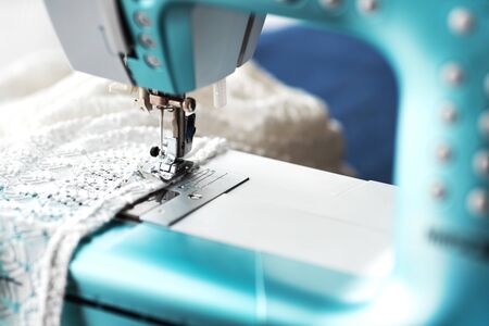 Sewing machine with denim and thread for sewing, close-up. The working process. Part of a sewing machine with blue cloth.の写真素材