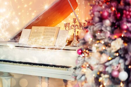Christmas holiday at home in a cozy atmosphere while playing the piano with candles and decorated fir tree.の写真素材
