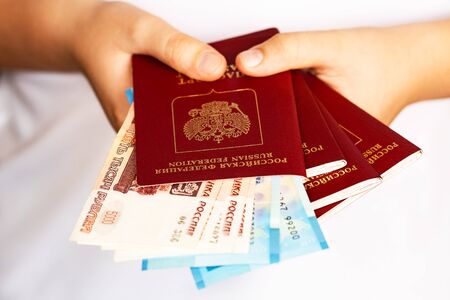 A Russian passport and money in the hands of a person for travel and shopping in another country.の写真素材