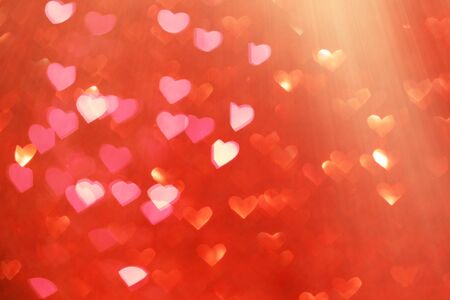 Red holiday bokeh in the form of a heart textured glitter background blurred from above.の写真素材