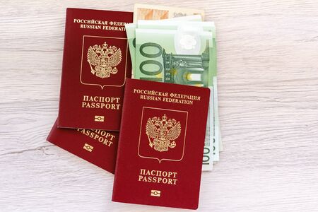 Russian passports with foreign money for purchases abroad, travel and entertainment. The money inside the passport is on a bright table.の写真素材