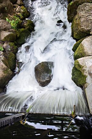 A beautiful waterfall in a forest landscape flowing down stones. Frame with selective focus, blur water.の写真素材