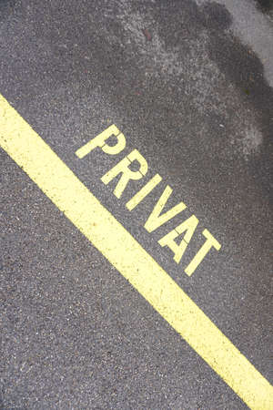 Private sign painted on asphalt with yellow line, conceptual image for property protection.の写真素材