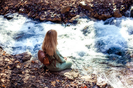 Portrait of a young happy woman tourist on a lake in the autumn forest.