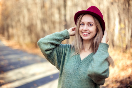 Close-up portrait of a young woman in a red hat against the backdrop of an autumn forestの写真素材