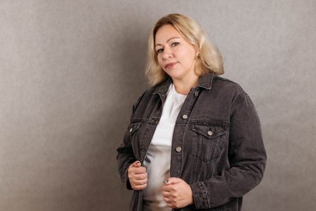 Blonde plus size in white T-shirt and black denim jacket smiles against the backgroundの写真素材