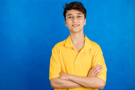 Close-up portrait of a smiling young man in a yellow T-shirt on a blue backgroundの写真素材