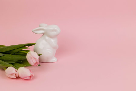 Easter card with pink tulips and a toy rabbit on a pink background, copy space.の写真素材