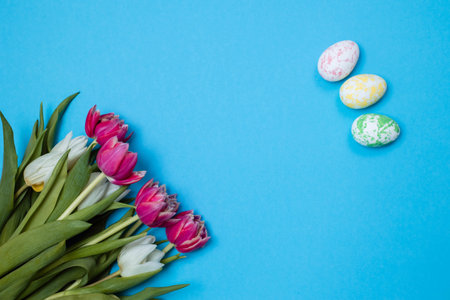 Colorful Easter eggs and a bouquet of flowers on a blue background, copy space, easter card.の写真素材