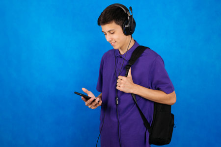Portrait of a young student with a school bag, smartphone and headphones.の写真素材
