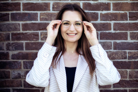 Portrait of a young woman with glasses, holding glasses with her hands near her face, close-upの写真素材