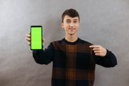 Portrait of a smiling young man with a phone in her hands on a grey background, chroma keyの写真素材