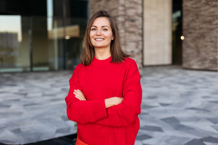 Portrait of a young beautiful woman smiling on the street against the backdrop of a modern building in the cityの写真素材