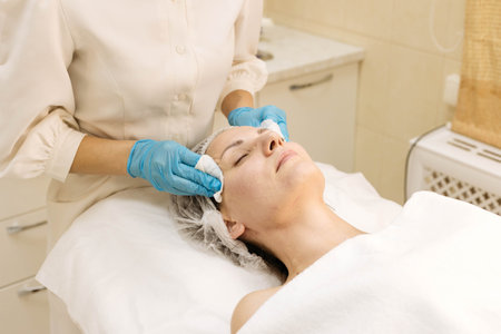 Skin cleansing with cotton pads in the beauticians office. Young woman lies on procedures at the beautician. Close upの写真素材