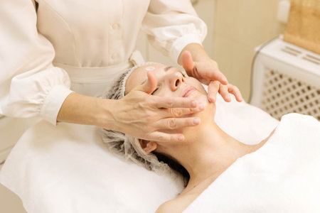 Cosmetologist applying face cream to patient after mesotherapy, biorevitalizationの写真素材