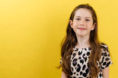 Portrait of a girl of a cute teenage girl on a yellow background, smiling looking at the camera, copy space, close upの写真素材