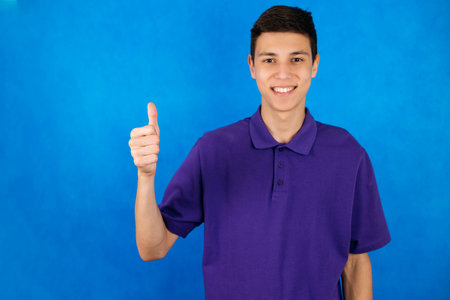 Close-up portrait of a young man on a blue background, shows the index finger up, copy spaceの写真素材