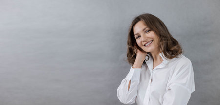 Cute young woman smiling, looking at camera on grey background, close-up, banner, copy spaceの写真素材