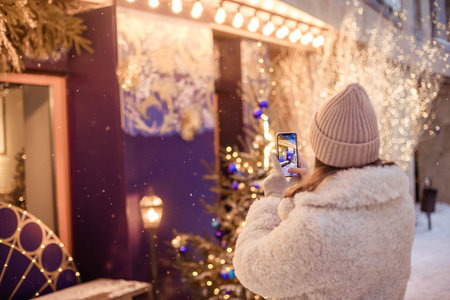 Young female tourist taking pictures of New Years decorations in the cityの写真素材