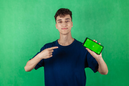 Young man with smartphone in hand, pointing at smartphone screen, chroma key