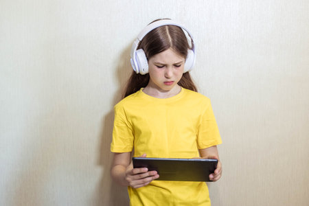 Portrait of a teenage girl in headphones and with a tablet in her hands, copy space, looking down