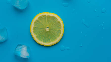 Creative summer background composition with lemon slice and ice cubes. Minimal concept of lemonade drink from top to bottom. Copy spaceの写真素材