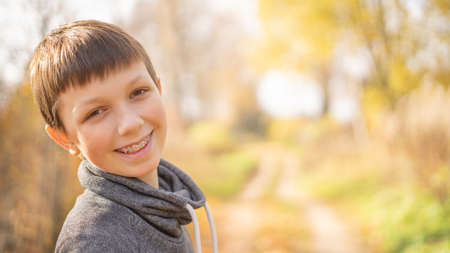 A cheerful teenager with braces on his teeth walks down the street on a bright day. Horizontallyの写真素材
