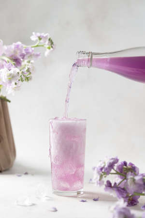 pouring lavender lemonade in glass with ice