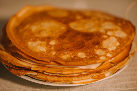 A stack of thin Russian hot pancakes blini  with steam emanating from them.