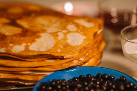 A stack of thin Russian hot pancakes blini  with currants.