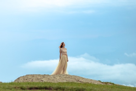 A girl in a tulle and topi skirt stands in the rain among the rocks.の写真素材