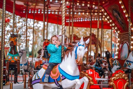 Little girl in a childrens amusement park on a carousel.