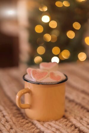 Homemade cocoa with marshmallows in an iron mug on a background of blurry lights. Christmas concept.の写真素材