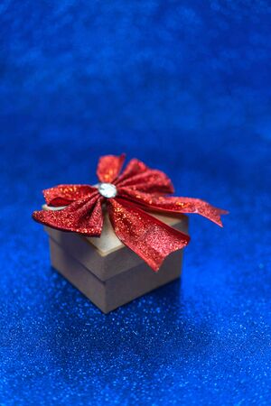 Gift box with shiny red ribbon over a glitter blue background. Birthday concept.の写真素材