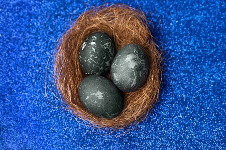 Painted chicken easter eggs with natural hibiscus dye, similar to sea stones, on a classic blue background, copy space.の写真素材