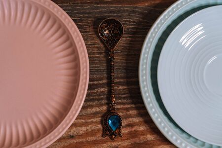 Three dishes of pink and blue, and a spoon with a blue crystal on a dark wooden background.の写真素材