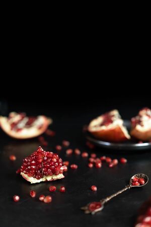 Some red juicy pomegranate, whole and broken, on a dark rustic wooden table. Vegan concept.の写真素材
