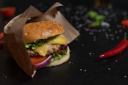 Fresh burger cooked on a barbecue outdoors in kraft paper. Cookout american barbecue food. Big hamburger with meat and vegetables close-up. Street food, fast food.の写真素材