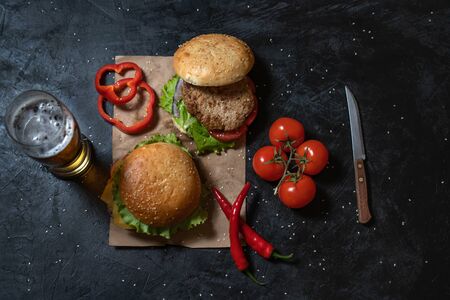Two fresh hamburger with steak, salad on a background of blurred glass of light beer on a black background. View from above. Flat lay.の写真素材