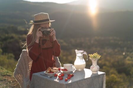 A girl outdoors takes pictures of breakfast, milk, cheesecakes.の写真素材