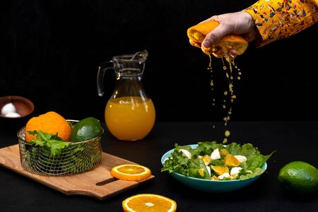 Cooking orange salad with lettuce, mozzarella cheese. Hand squeezes orange juice.の写真素材