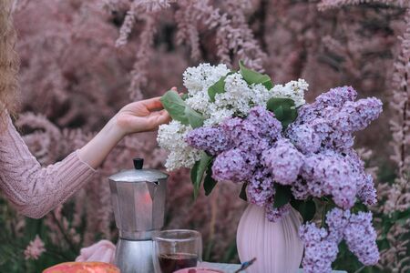 Female hand touches beautiful lilac inflorescences in the summer garden at breakfast.の写真素材