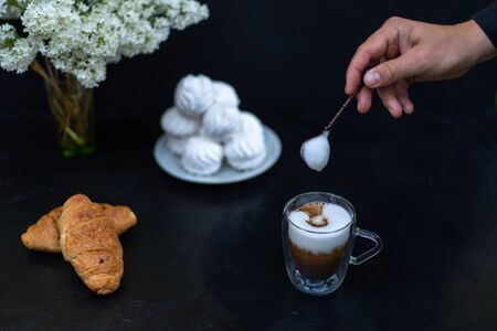 Cup of cappuccino with coffee beans and croissant, marshmallow and a bouquet of flowers. Breakfast.の写真素材