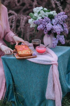 Rustic pie on a wooden table with cream, coffee pot and flowers - lilac.の写真素材