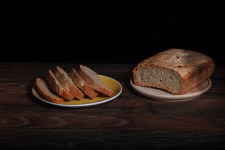 Rustic bread sliced in slices on a black board. Rural kitchen or bakery - background with free text space.の写真素材