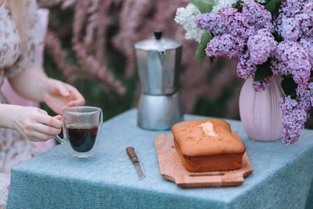 Rustic pie on a wooden table with cream, coffee pot and flowers - lilac.