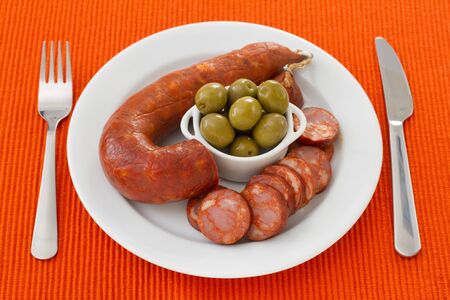 sausages with olives on the white plateの写真素材